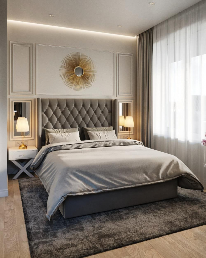 бело-серая спальня с зеркалом в золотой оправе с лучиками над мягким изголовьем кровати и двумя зеркалами по сторонам кровати.jpg